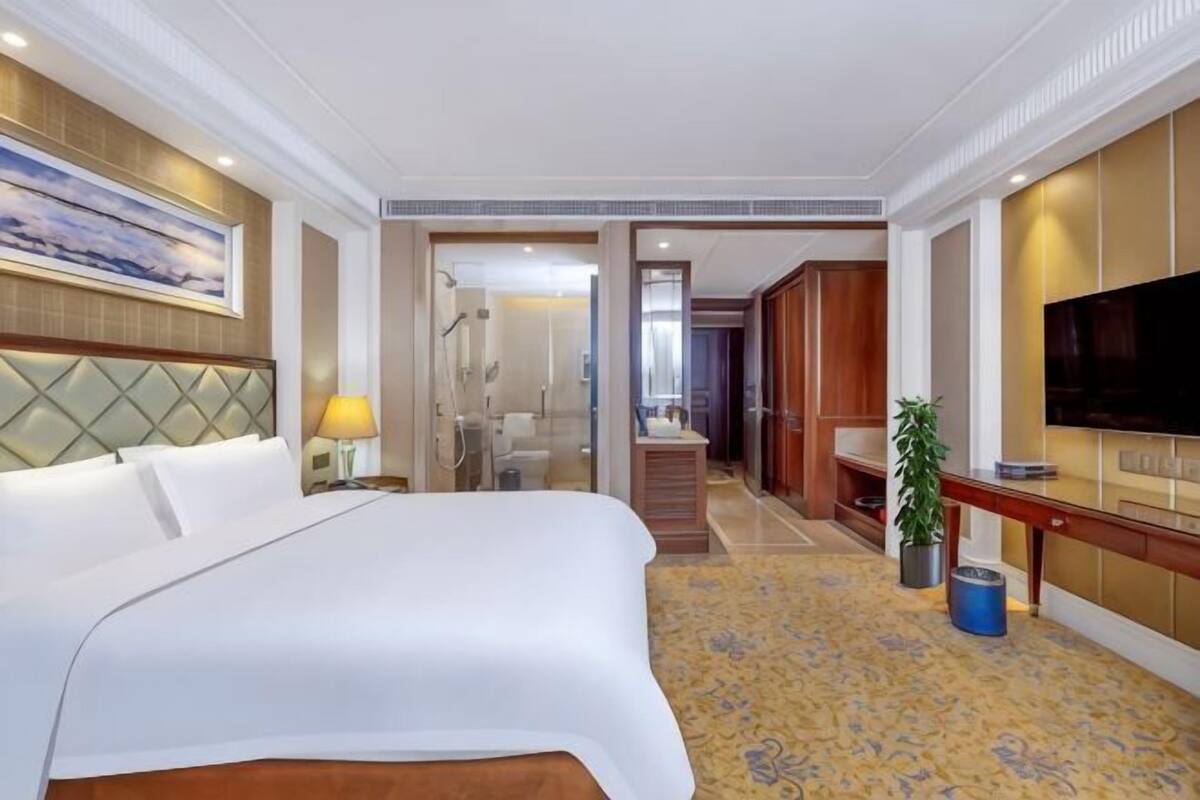 A hotel room with a large bed, a TV, a desk, and a bathroom.