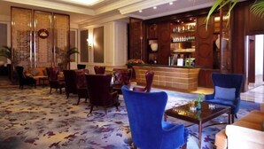 A lobby with a reception desk, seating area, and a bar. - Noble Hotel (Shanwei)