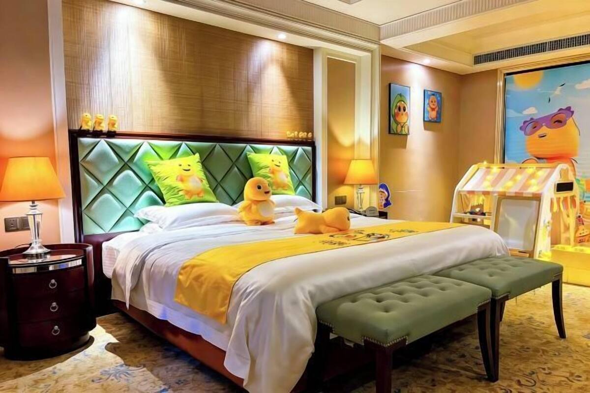 A hotel room with a bed, bedside lamps, a bench, and a wall with artwork.