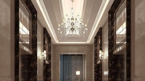 A hallway with a chandelier, marble walls, and a patterned door. - Noble Hotel (Shanwei)