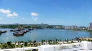 A waterfront view with boats docked, a marina, and a cityscape in the background. - Noble Hotel (Shanwei)