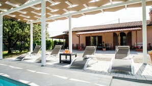 Ein überdachter Außenbereich mit Liegestühlen und einem Pool.