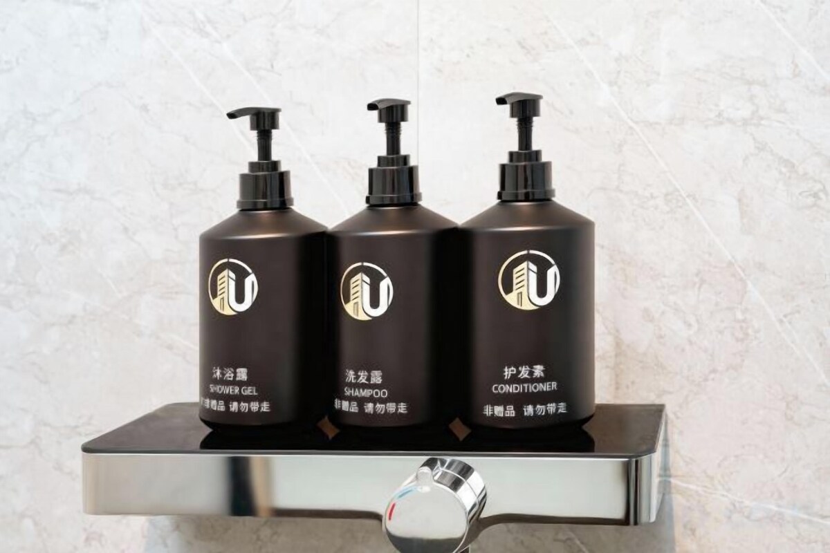 Tre flaskor med produkter för personlig hygien står på en hylla av metall.