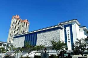 A building with a large mural on the facade, a blue awning, and a sign with Chinese characters. - Urban Convenient Hotel (Guangdong University of Petrochemical Technology Branch) (Maoming)