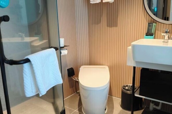 Un baño moderno con cabina de ducha de vidrio, inodoro blanco y lavabo con espejo.