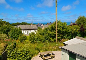 Surrounded by lush greenery and a distant sea view, this serene home offers a tranquil outdoor space.