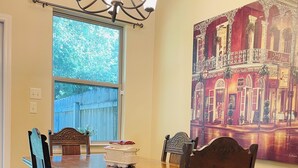 A dining area with a wooden table and chairs, a chandelier, and a large painting of a building on the wall. - Beech St. fenced back yard, central location, garage (Covington)