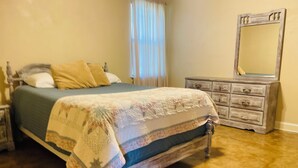 A bedroom with a bed, a dresser, and a mirror.