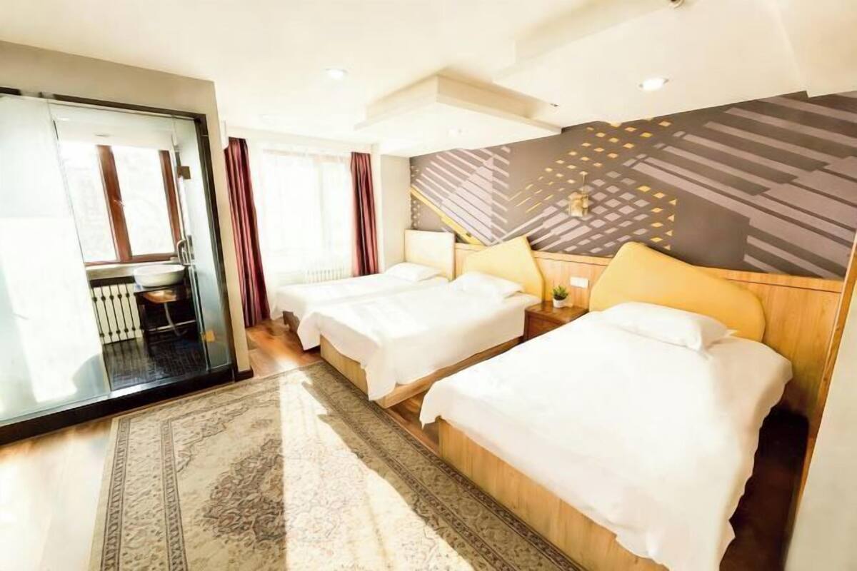 A hotel room with two beds, a bathroom, and a view of the city.