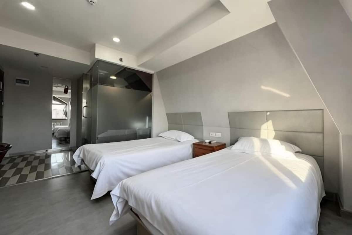 A hotel room with two beds, a checkered floor, and a modern design.