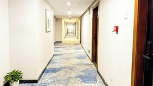 A hotel hallway with a patterned carpet, doors on both sides, and a plant in the corner. - Laike Hotel (Harbin Railway Station Museum) (Harbin)