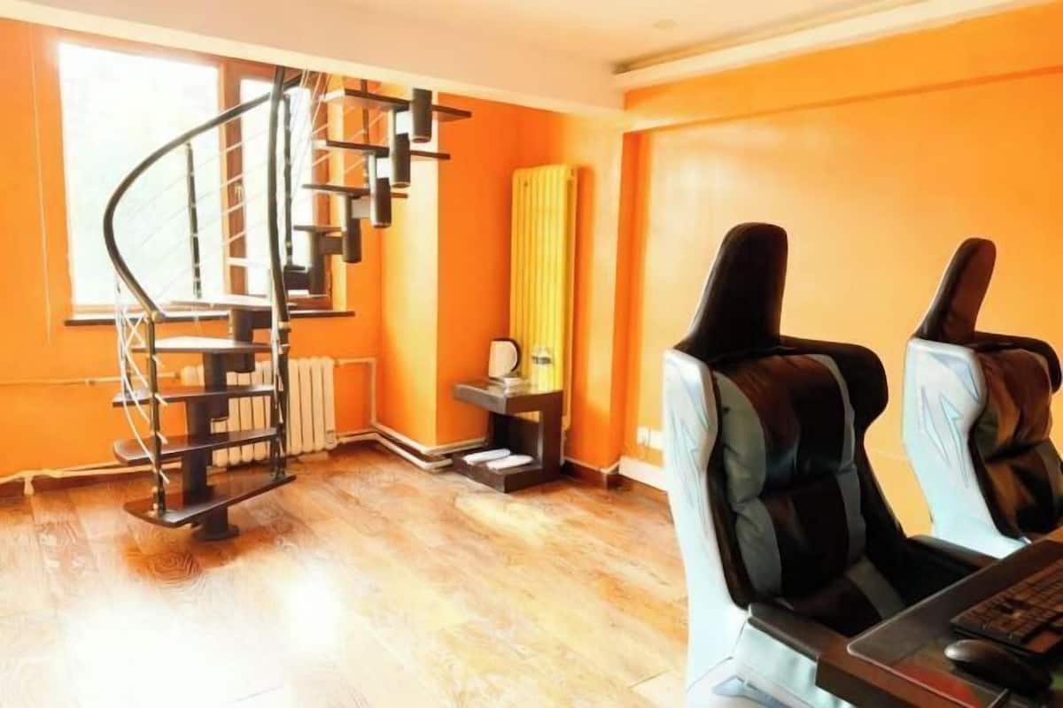 A room with a spiral staircase, a desk with a computer, and a window.