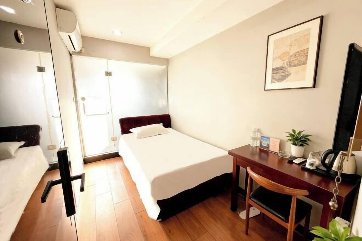 A hotel room with a bed, desk, chair, and a framed picture on the wall.