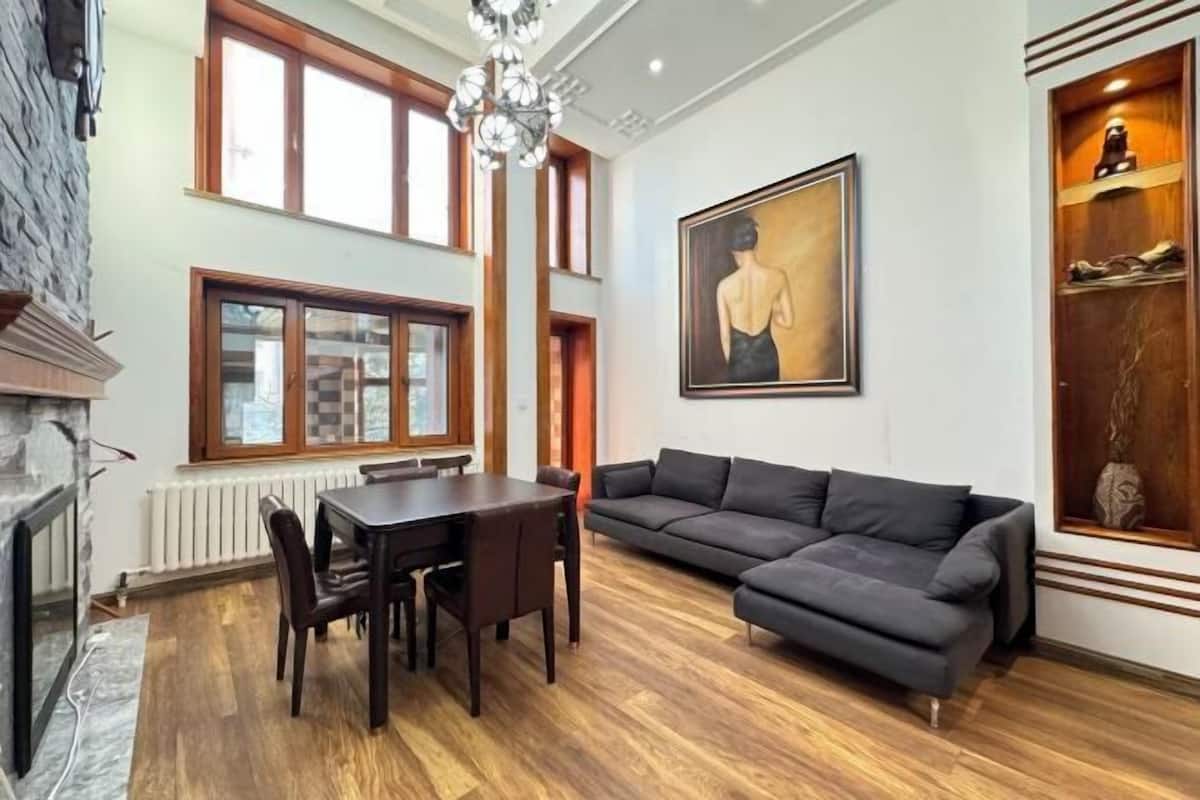 A modern living room with a dining table, sofa, and fireplace.