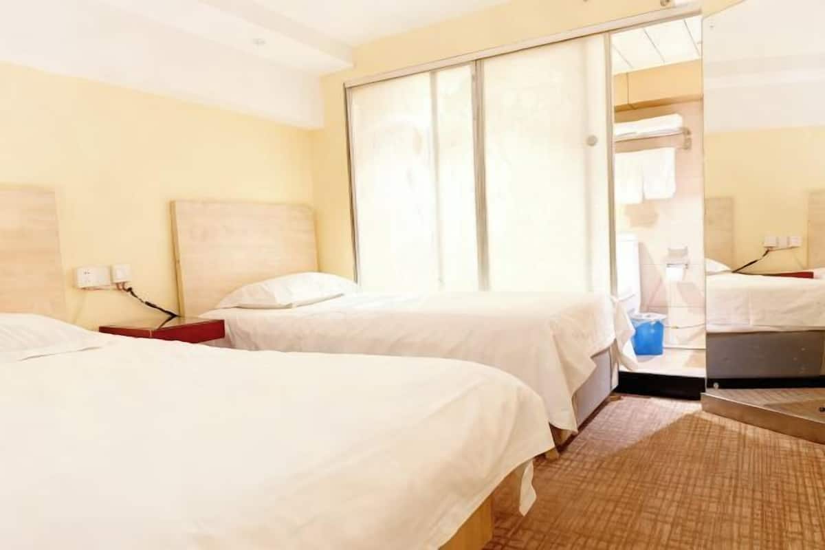 A hotel room with two beds, a sliding door, and a small desk.