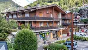 Un hôtel à plusieurs étages doté de balcons, d’un panneau indiquant la présence d’une station de ski à proximité, et offrant une vue sur une région montagneuse.