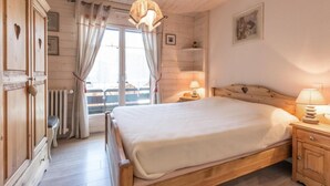 Une chambre à coucher avec un cadre en bois, comprenant un lit, des lampes de chevet, un radiateur et une fenêtre avec des rideaux.
