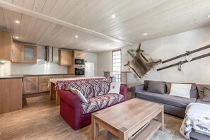 A living room with a sofa, a coffee table, and a kitchen area with wooden cabinets and appliances.