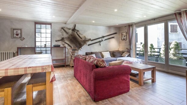 Un salon chaleureux avec un canapé rouge, des meubles en bois et une grande moquette en fourrure.