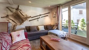 Un salon chaleureux avec un canapé, une table basse en bois et un tapis en fourrure fixé au mur.