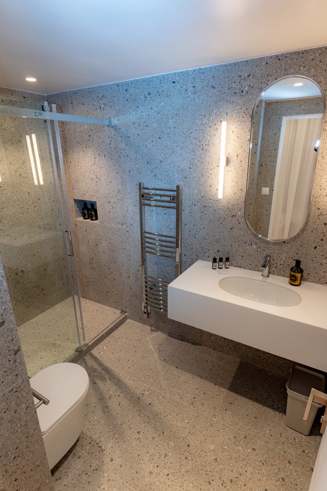 A modern bathroom with a glass-enclosed shower, a white sink, and a large mirror.