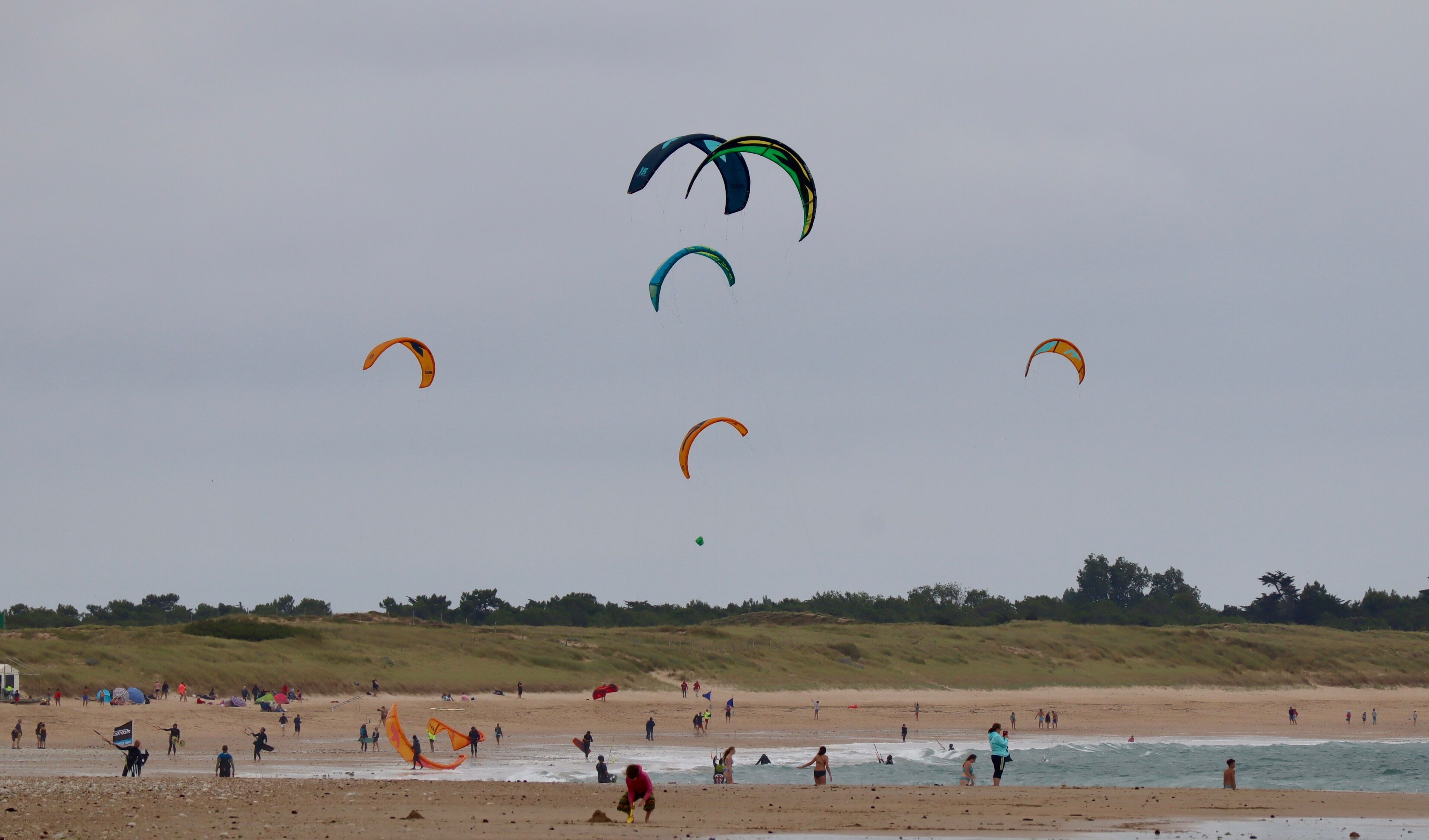 A beach with people engaging in various activities, including kite flying.