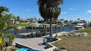 A marina with kayaks, a dock, and a boat. - Relaxing 3 Br-2 Ba cottage on canal with heated pool & hot tub. (Cape Coral)