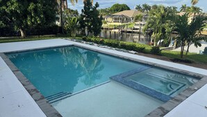 A rectangular swimming pool with a tiled edge, surrounded by a concrete deck. - Relaxing 3 Br-2 Ba cottage on canal with heated pool & hot tub. (Cape Coral)