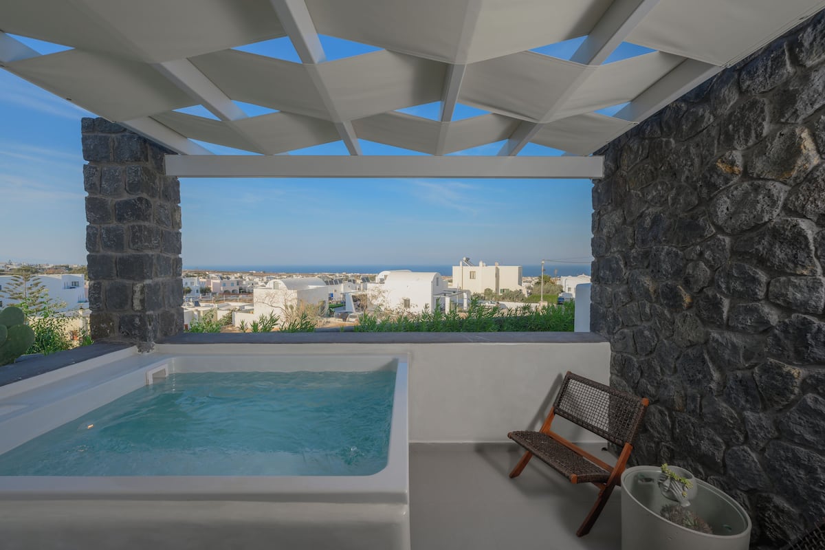 A rooftop terrace with a hot tub, a chair, and a view of the city.