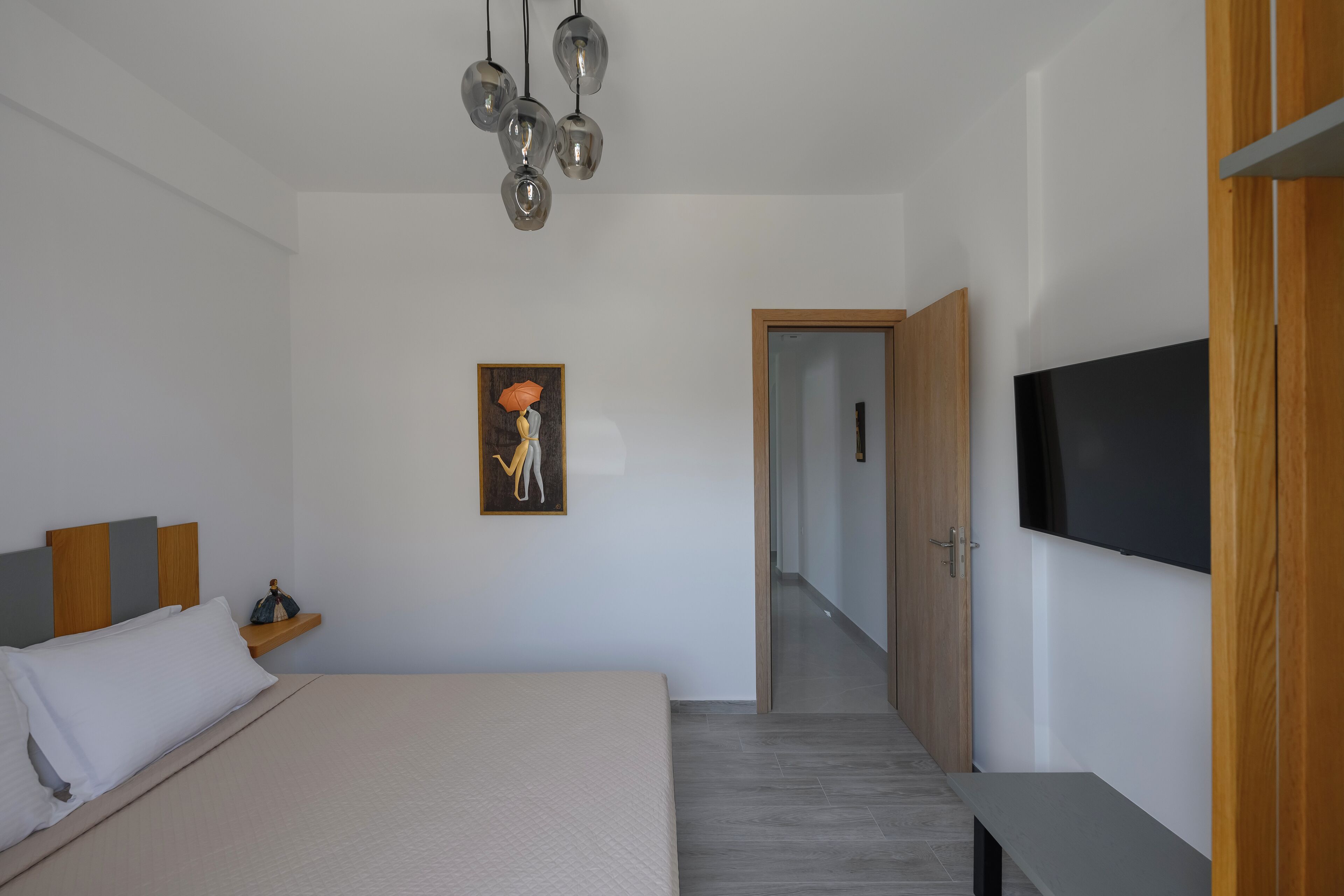 A modern bedroom with a bed, a TV, and a painting on the wall.