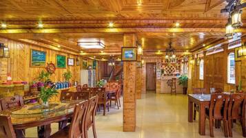 A wooden-paneled dining area with tables and chairs, a bar area, and a staircase leading to an upper level.