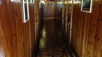 A narrow corridor with wooden walls and doors, leading to a central area.