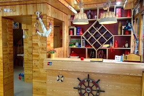 A wooden interior with a wooden counter, nautical-themed decor, and shelves with various items.