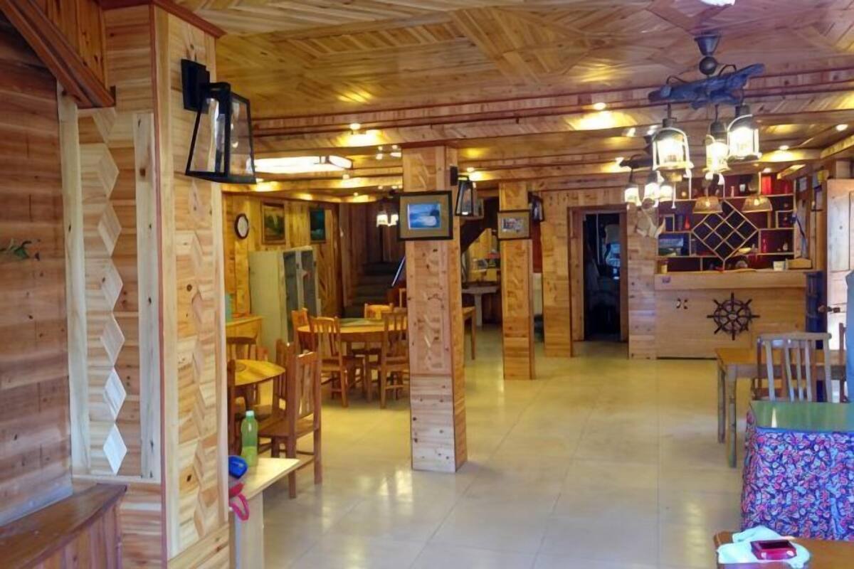 A wooden interior with a dining area, a bar, and a staircase leading to another level.