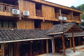 Un edificio tradicional de madera con varios balcones, unidades de aire acondicionado y una zona de estar exterior cubierta.