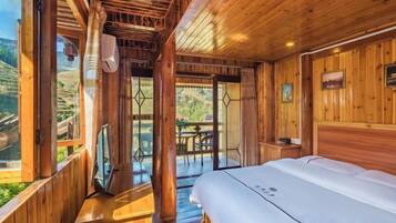 Habitación de cabaña de madera con cama, televisor y balcón con mesa y sillas.