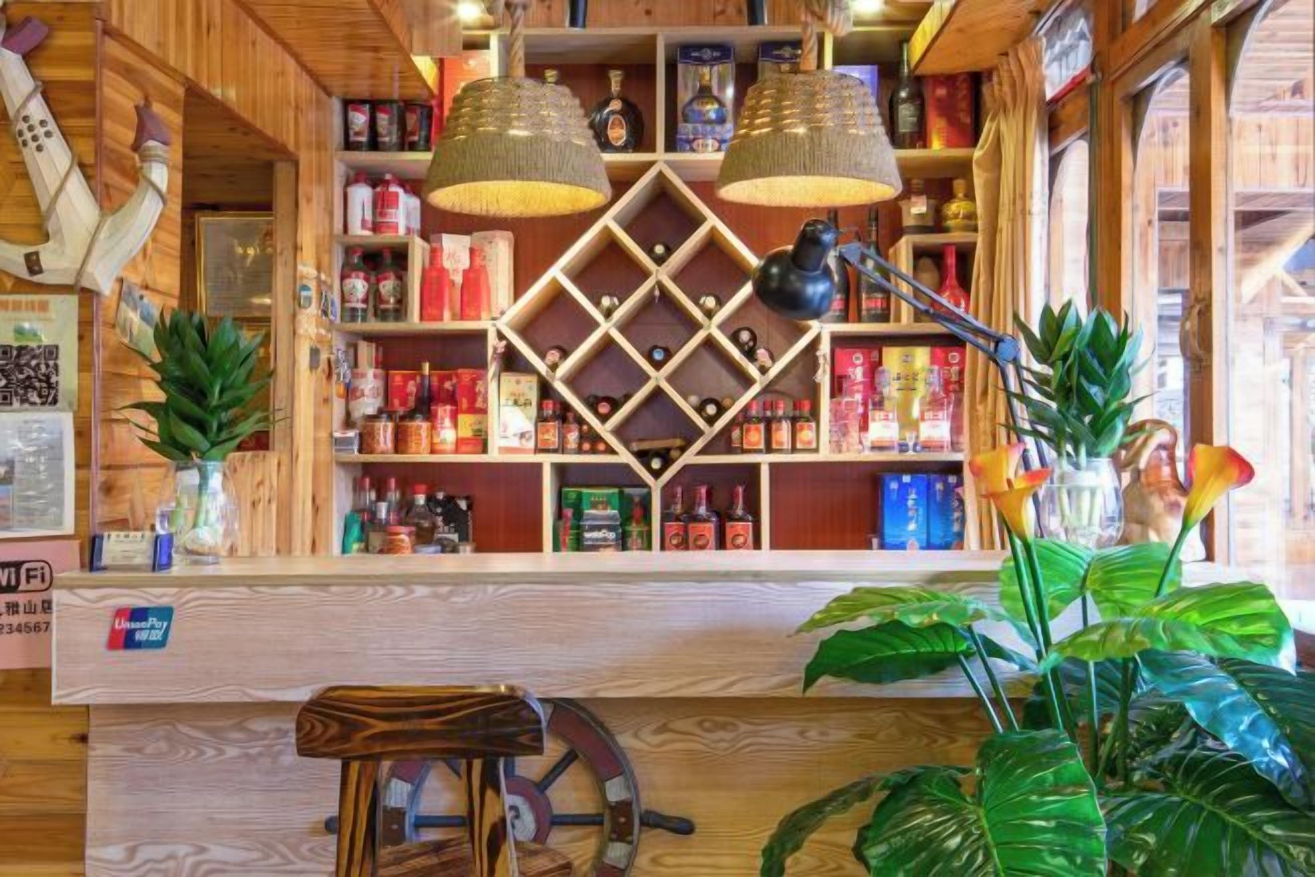 A bar area with wooden shelves, hanging lights, and potted plants.