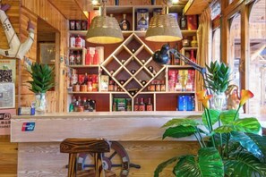 Zona de bar con estantes de madera, luces colgantes y plantas en macetas.