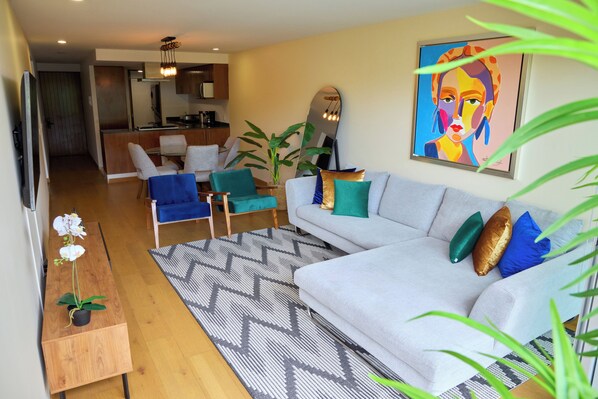 Ein modernes Wohnzimmer mit Sofa, Sesseln, einem Couchtisch und einem Essbereich im Hintergrund.
