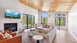 Amplia sala de estar con chimenea, ventanas grandes y un ventilador de techo moderno.