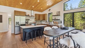 Una cocina moderna con una isla grande, armarios de madera y vistas al bosque.