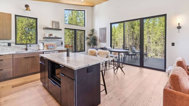 Una cocina moderna con una isla central, ventanas amplias y un comedor con vistas al exterior.