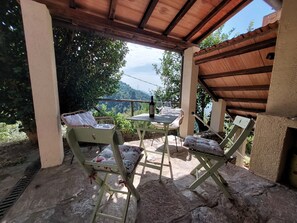 Un espacio de estar al aire libre techado con una mesa y sillas, con vistas a un paisaje pintoresco.