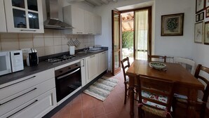 A kitchen with white cabinets, a stove, a microwave, and a dining table with chairs.