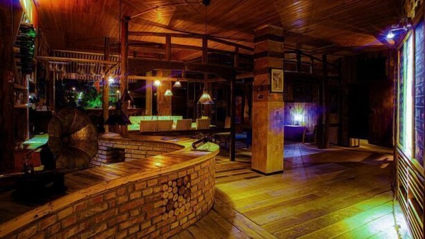 Un interior rústico con una zona de bar de madera, un mostrador de ladrillo y un techo de madera.