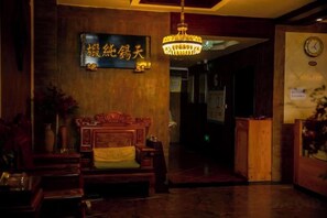 A reception area with a wooden bench, a hanging chandelier, and a wall-mounted sign. - Boao Yingke Hotel (Dali City)
