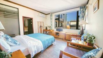 Una habitación de hotel con cama, escritorio, silla y un ventanal grande.