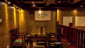 A dimly lit room with wooden furniture, including a table and chairs, and a framed sign on the wall. - Boao Yingke Hotel (Dali City)