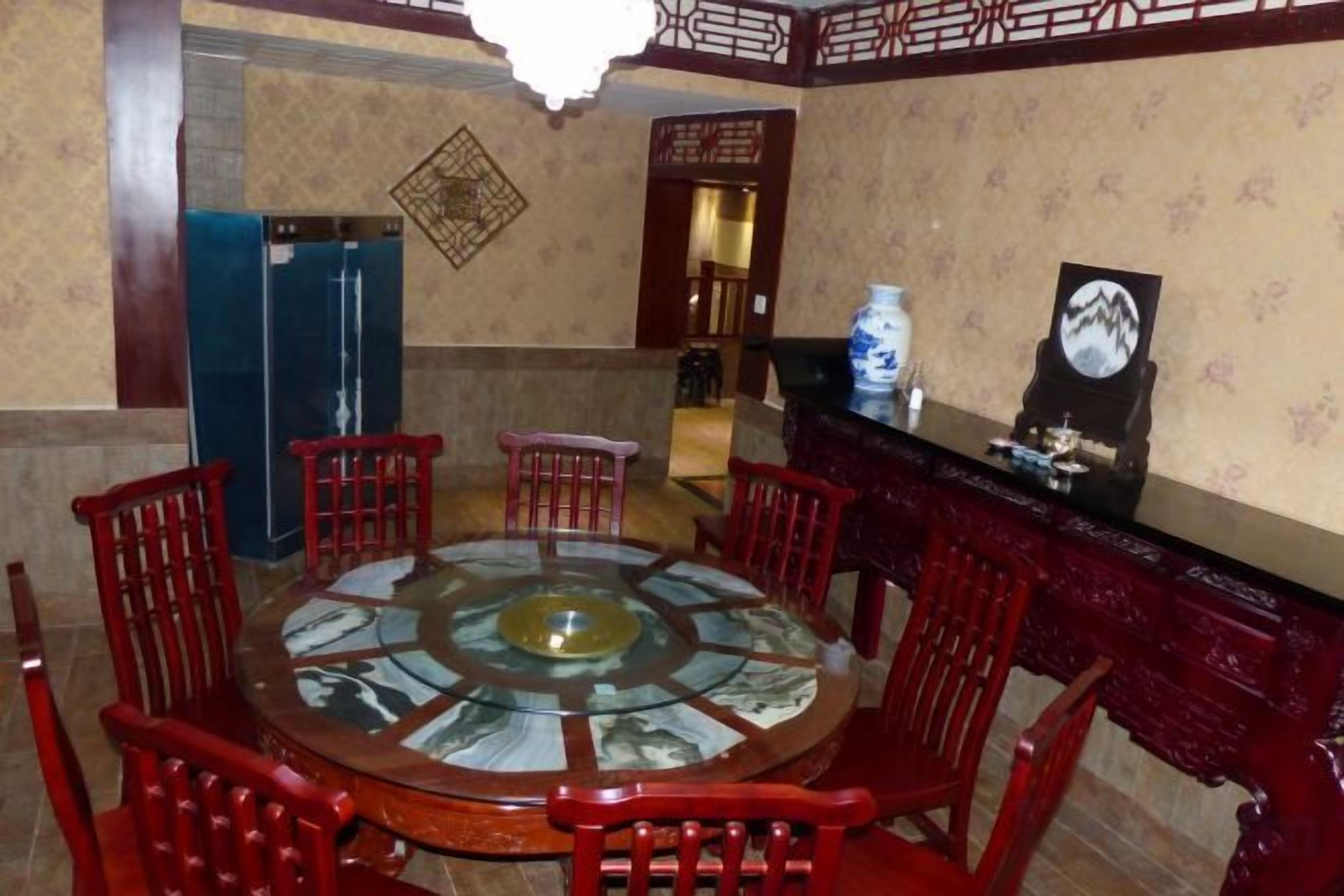 A dining area with a round table surrounded by chairs, a blue refrigerator, and a decorative wall piece.