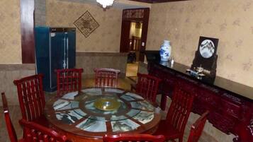 A dining area with a round table surrounded by chairs, a blue refrigerator, and a decorative wall piece.